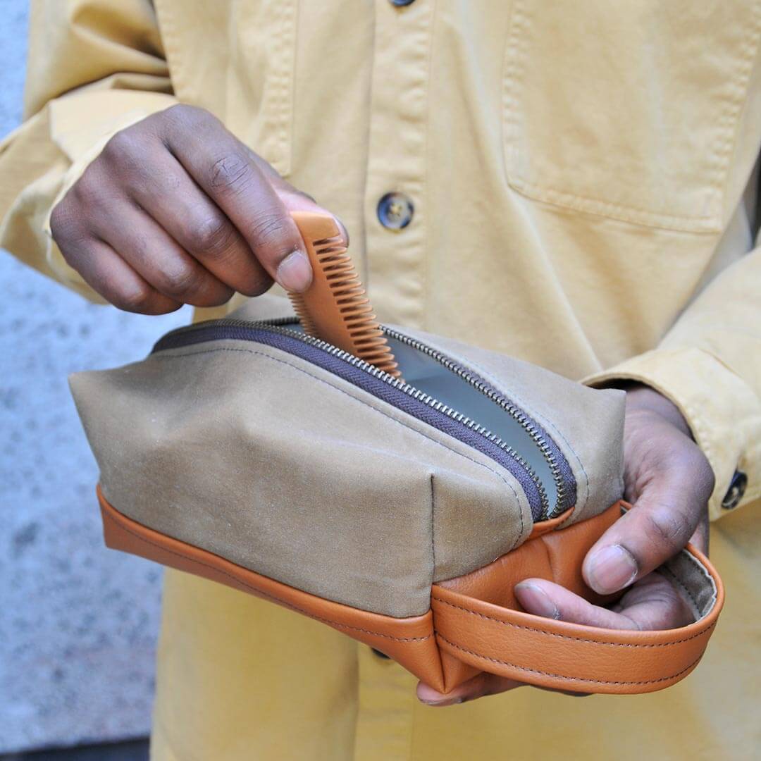 Man putting comb into leather washbag