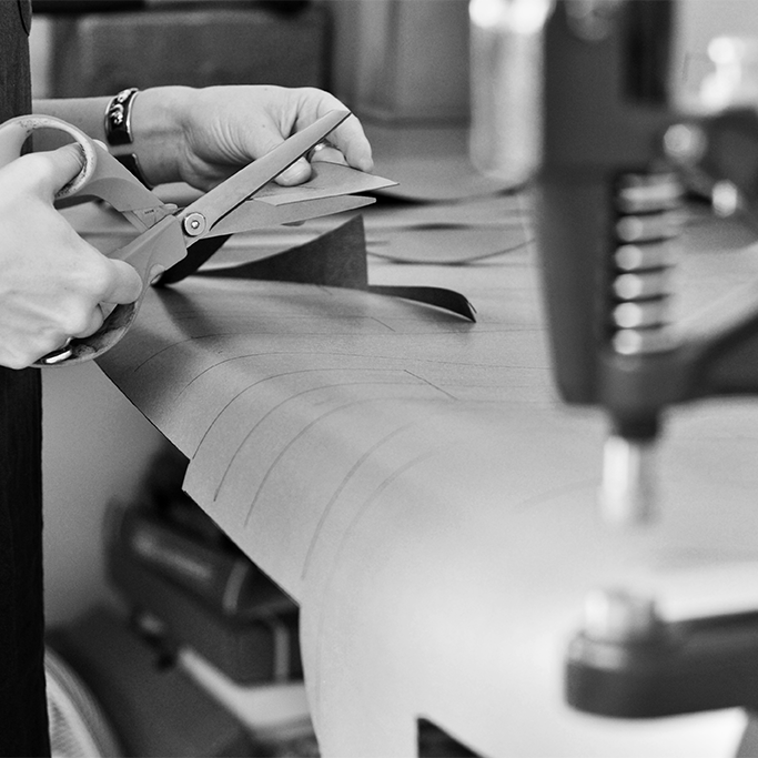 Black and white image of hands cutting fabric in a studio. Handmade recycled leather handbags, backpack and accessories made from sustainable materials in Bristol, UK.