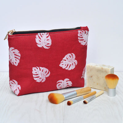 Red linen make up bag in monstera leaf print with brushes and soap props