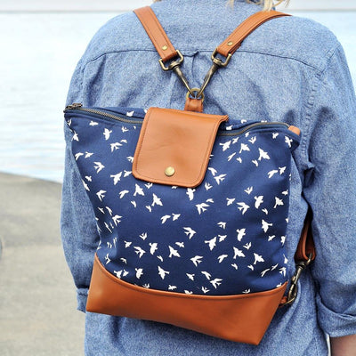 Woman in denim shirt wearing Recycled leather convertible crossbody backpack in navy bird fabric